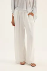 Pantalón de lino color beige, de corte palazzo y terminación con flecos.