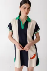 Vestido corto tejido en jersey liviano de algodón y acrílico, con diseño tipo polo y fit holgado. Presenta rayas verticales en color marrón y crudo, bordado XL de un ají y terminaciones en color amarillo.