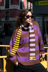 Sweater de punto a rayas horizontales marrones, violetas y amarillas, de corte holgado y cuello redondo.