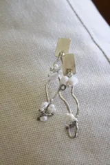 Aros colgantes de alpaca color plateado con perlas de río blancas.