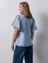 Blusa color beige de crepe, marca Batía, con cuello a la base y escote en V. Manga corta amplia con bordados.