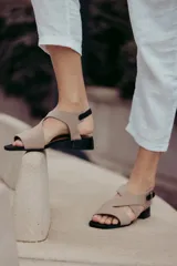 Sandalias de cuero color beige con tiras cruzadas y hebilla lateral. Taco cuadrado color marrón oscuro.