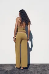Pantalón ocre de algodón compacto, tiro medio, cintura elástica con cordón ajustable, pierna ancha y efecto lavado.
