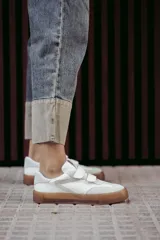Zapatillas urbanas blancas con detalles en gris y suela color caramelo. Presentan cierre con tiras de velcro.