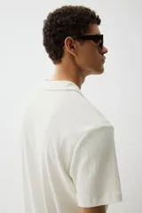 Remera blanca de punto texturizado con cuello y miniabertura en V.