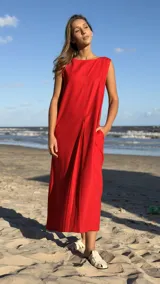 Vestido largo rojo sin mangas, de lino con pespuntes en tono más oscuro y pinzas. Tiene cuello redondo y bolsillos laterales.