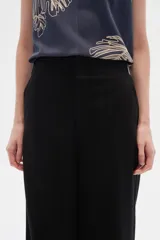 Pantalón de lino negro, de tiro alto y corte recto ancho, con bolsillos laterales.