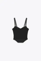 Top negro tipo corsetero con escote corazón y tirantes finos. Presenta varillas forradas que realzan la figura y cierre lateral con cremallera oculta.