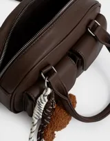 Cartera bowling marrón chocolate de cuerina con doble bolsillo frontal con solapa y broche, cierre superior, correa regulable y desmontable, manijas superiores y charm de perrito.