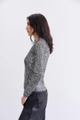 Remera negra de mangas largas con lentejuelas aplicadas en toda la prenda, escote redondo y forrería interna.