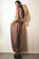 Pantalón bombacho marrón de tejido fluido, tiro medio con cintura elástica ajustable con cordones, bolsillos laterales ocultos y bajo abullonado con elástico interior.