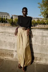 Top negro de tejido de punto, cuello redondo, manga corta y hombreras marcadas. Presenta un bajo ancho y ajustado.