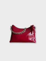 Cartera de cuero natural color rojo con correa de cadena plateada. Tiene bolsillo interior con cierre y forro.