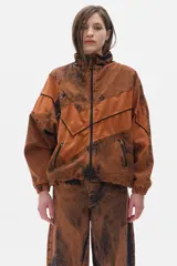 Campera estilo olímpica de jean color marrón con efecto lavado. Corte oversized, con elástico en la cintura, cuello alto y bolsillos al frente con cierre.