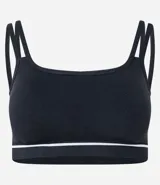 Top deportivo negro sin costuras, con escote asimétrico y doble tirante en los hombros. Presenta una delgada línea blanca horizontal en la banda inferior.