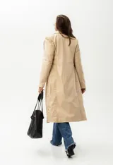 Trench largo de cuero color beige con forro azul, cuello clásico, cierre frontal con botones y bordado de las "S" en el frente.