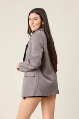 Blazer negro de corte sastre, con solapas de muesca, cierre frontal con un botón y bolsillos delanteros con solapa.