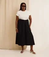Vestido midi bicolor, con parte superior color crema y falda negra, confeccionado en tejido de punto rib de algodón. Tiene escote redondo y mangas cortas.
