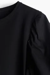 Top negro de punto de algodón con cuello redondo y bajo recto. Mangas globo cortas en tejido de algodón con forro de punto y ribete elástico.