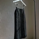 Vestido negro con estampado de ondas plateadas y tirantes de cadena metálica.