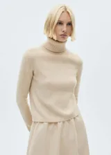 Sweater color beige de tejido de punto con cuello alto y mangas largas.