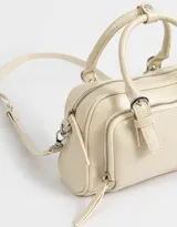 Cartera bowling color crudo con efecto craquelado, doble asa corta, correa larga regulable y desmontable, cierre superior, bolsillo frontal con cierre y hebillas decorativas.
