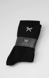 Medias negras de algodón, estilo 3/4, con puño acanalado. Presentan un bordado blanco en la parte superior que simula unas tijeras cruzadas y texto en la planta que dice "Ropa sin género para seres humanos".