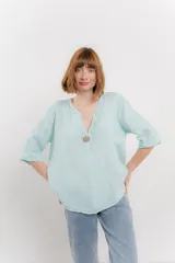 Blusa celeste de lino, con escote en V, manga tres cuartos y botón de madera.