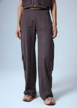Pantalón cargo marrón de gabardina, con cierre metálico lateral, elástico en cintura trasera, recortes delanteros y bolsillos tipo cargo.
