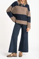 Sweater de tejido de punto grueso, color marrón y azul marino, con diseño de rayas horizontales anchas. Presenta cuello polo y abertura frontal con dos botones nacarados.