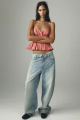 Top con estampado a rayas verticales rojas y blancas, escote pico, tirantes finos ajustables, detalle de pliegues y cierre frontal con botones.