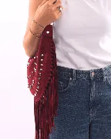 Bolso de hombro tipo boho, color bordó, confeccionado en gamuza con tachas plateadas y flecos largos. Tiene correa doble para usar al hombro o cruzado, forro interior y bolsillo interno.