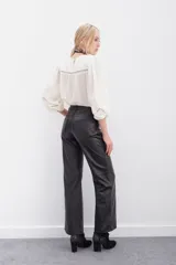 Pantalón de cuero ovino color negro, de corte jeanero con calce oxford y tiro medio. Tiene acceso delantero con botón metálico y cierre, y bolsillos delanteros y traseros.