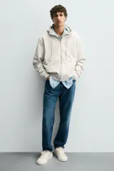 Zapatillas deportivas blancas de caña baja con detalle de color gris en el talón y suela con volumen.