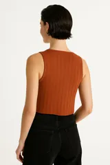 Top sin mangas color crema, de punto crochet con rayas verticales, cuello en v y cierre frontal con broches.