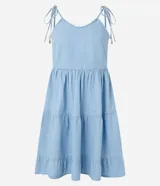 Vestido corto de jeans celeste, con breteles finos con lazos, escote en U, espalda descubierta y falda de tres niveles con volados.