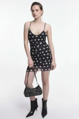 Vestido corto negro con lunares blancos, breteles finos y volados horizontales.