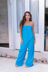 Conjunto de dos piezas color beige claro, compuesto por un top strapless con bajo asimétrico y un pantalón ancho de tiro alto.