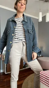 Camisa de pana azul con cuello clásico, cierre frontal con botones dorados, bolsillos con solapa y detalles de strass en cuello y bolsillos. Mangas largas con puños abotonados.
