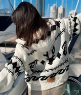 Camperón tejido oversize con capucha, bolsillos y estampa de ciervo.