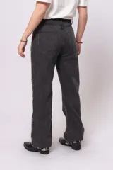 Pantalón de jean negro de corte recto con tachas plateadas en los bolsillos y a lo largo de las costuras laterales.
