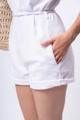 Mono corto blanco con breteles finos, escote en V y cinturón con hebilla circular.