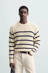 Sweater de punto color crema con rayas horizontales azul marino, cuello redondo y manga larga.