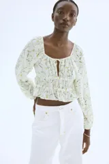 Blusa corta blanca con estampado floral, de tejido arrugado, escote cuadrado elástico con cordón ajustable, mangas globo largas con puños elásticos y costuras elásticas en la cintura para un efecto fruncido.