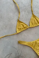 Conjunto de bikini verde esmeralda, con corpiño triangular de atar al cuello y espalda, con almohadillas desmontables, y bombacha colaless con laterales fijos.