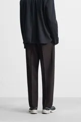 Pantalón de vestir negro de corte recto, con cintura elástica, pliegues frontales, bolsillos laterales y traseros.