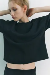 Top negro de punto canalé con cuello redondo y mangas cortas.