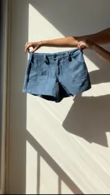 Short de denim celeste con bolsillos laterales y cierre frontal con botón.