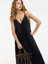 Vestido negro con escote en V y breteles finos. Corte evasé amplio con caída en picos.