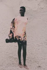 Vestido túnica con estampado floral en tonos rosados y negros, de tejido arrugado, silueta oversized, mangas largas con gran volumen y cuello redondo con abertura de cerradura y botón oculto en la nuca. Largo hasta la rodilla.